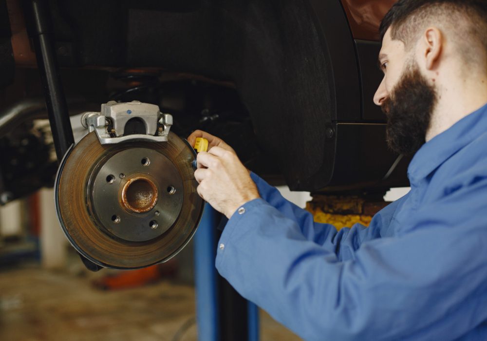 Mechanic with a tool. Wheel in hands of a mechanic. Blue work clothes.